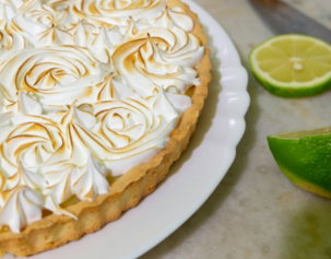 white icing cake with sliced of green citrus fruit on white ceramic plate